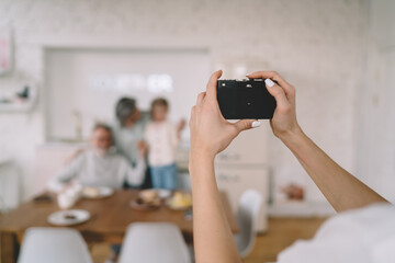 Crop woman taking photo of family on film camera