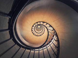 Abstract view of a circular staircase with black metal railing, inside the triumphal arch, Paris, France. Abstract background, a look up underneath an infinite swirl stairs