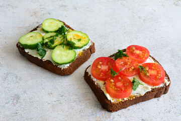 Two slices of bread with cucumber, tomato slices on top with ricotta and spices isolated 