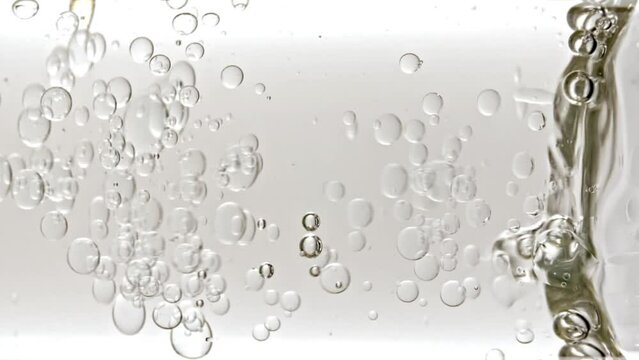 Transparent Cosmetic Gel Fluid With Molecule Bubbles and Oil Flowing in Glass Tube with Clear Liquid on White Background. Macro shot. Production Close-up. Slow Motion. High quality FullHD footage. 