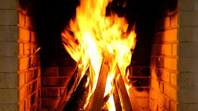 Burning firewood in fire-box of fireplace in country cottage. Rustic cooking oven with burning logs.
