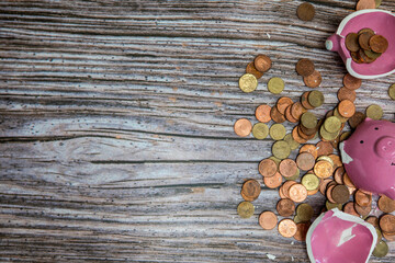 Broken piggy bank smashed into pieces with hammer, with cash and coins on wooden background top view with copy space, money savings concept