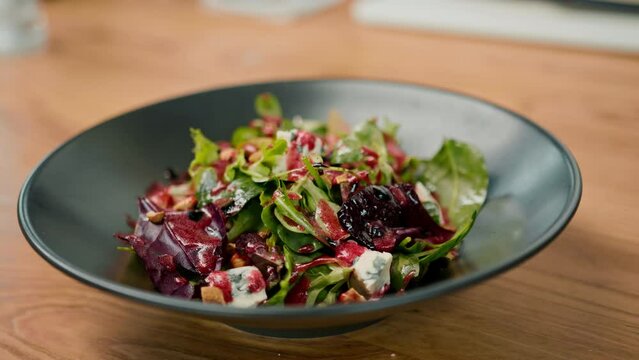 Professional kitchen, the chef serves salad with pear and cheese on the table doused with beetroot sauce healthy food 