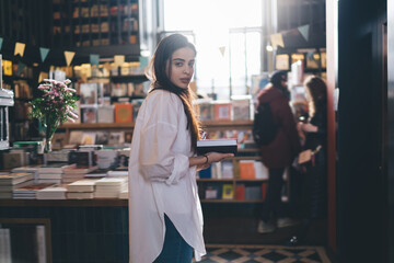 Charming woman with book walking in library