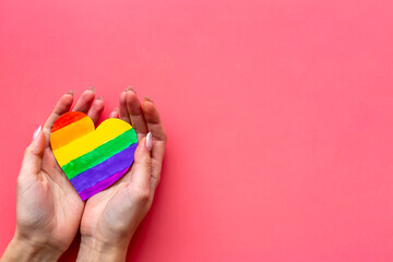 Female hands with rainbow LGBT colored heart paper cut. LGBT social rights concept.