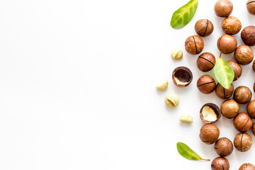 Shelled macadamia nuts with green leaves. Healthy snack background