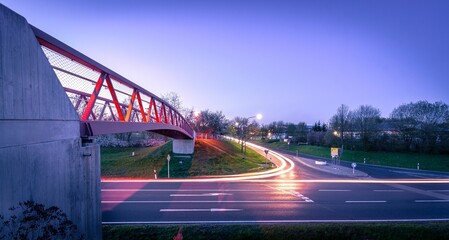 Long exposure of the lights of the cars on the road with a pedestrian bridge at sunset