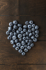 Blueberry in the shape of a heart on wood background is the concept for any kind of diet and healthy eating. Closeup, copy space for text, top view, flat lay