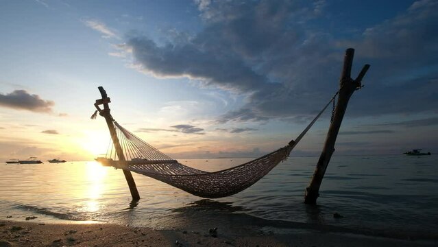 Wide angle video shot of a hammock net installed on the shallow sandy beach on Le Morne peninsula, Mauritius. Calm sunset time 4k footage.
