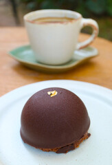 Closeup of Chocolate Mousse Dome Cakes with Blurry Coffee Cup in the Backdrop