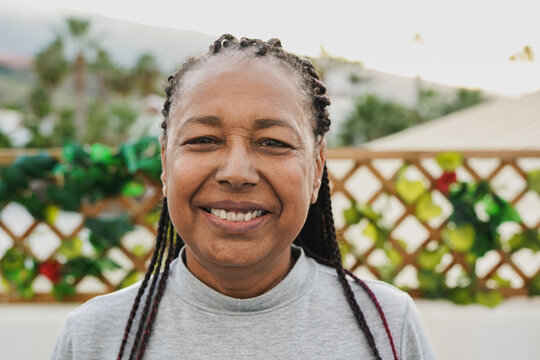 Portrait of happy senior african woman smiling on camera at home patio