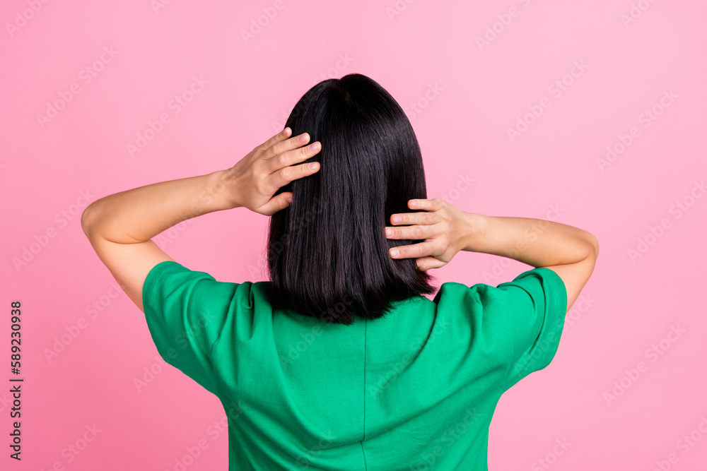 Wall mural Back view photo of gorgeous adorable woman straight hairstyle oversize t-shirt arms touching soft hair isolated on pink color background