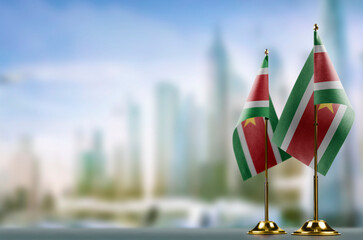 Small flags of the Suriname on an abstract blurry background