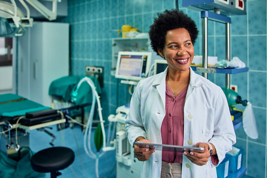 A smiling African doctor holding a digital tablet in the operation room.