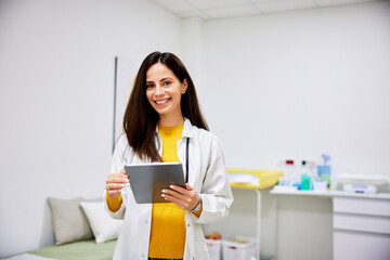 Portrait of a smiling female doctor with a  tablet in her hands in her ambulance.