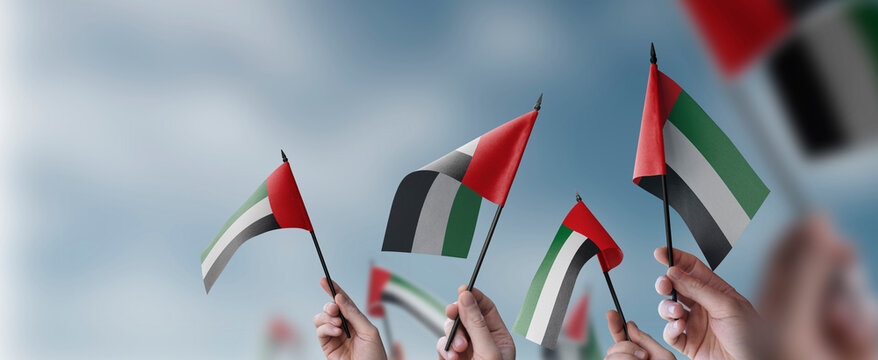 A group of people holding small flags of the Arab Emirates in their hands