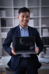 Portrait of Smiling young male employee feel euphoric with promotion offer in paperwork letter in office. a cheerful man sitting at his desk using smart phone at home office.