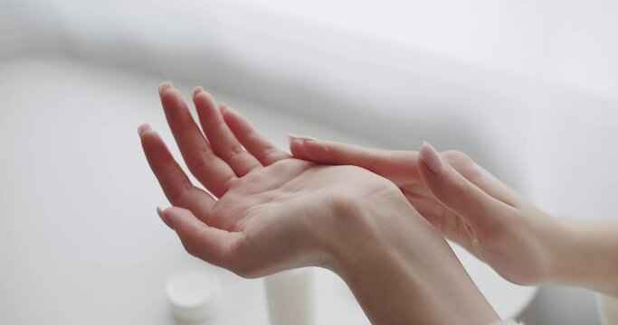 Female hands care. Close up. Spreading the applied moisturizing hand cream so that it gets soaked. Treatment dermatology and cosmetic with moisturiser. beautiful lady applying hand cream at home.