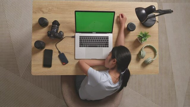 Top View Of Asian Woman Video Editor Sleeping While Using Green Screen Laptop And Smartphone Next To The Camera In The Workspace At Home
