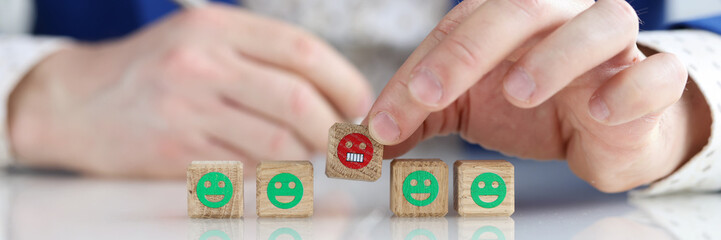 Male hand holding wooden cubes with angry emoji