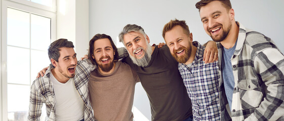 Group of happy male friends standing and hugging. Portrait of cheerful hipster men posing together...