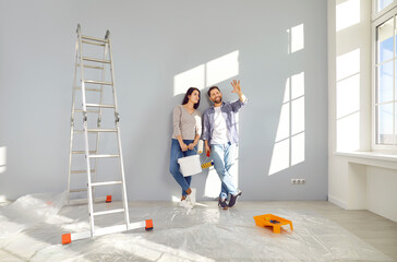 Young family couple doing renovations at home. Happy man and woman painting walls and decorating...