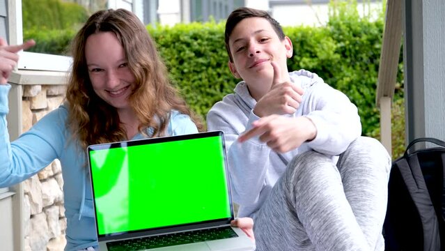 popular cool photo of teens holding laptop green edge chroma key boy and girl showing fingers ad laughing sincere smile shoulder backpack online learning teen life happy end fun entertainment games