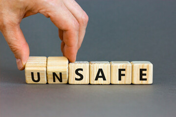 Safe or unsafe symbol. Concept word Safe Unsafe on wooden cubes. Businessman hand. Beautiful grey table grey background. Business safe or unsafe concept. Copy space.