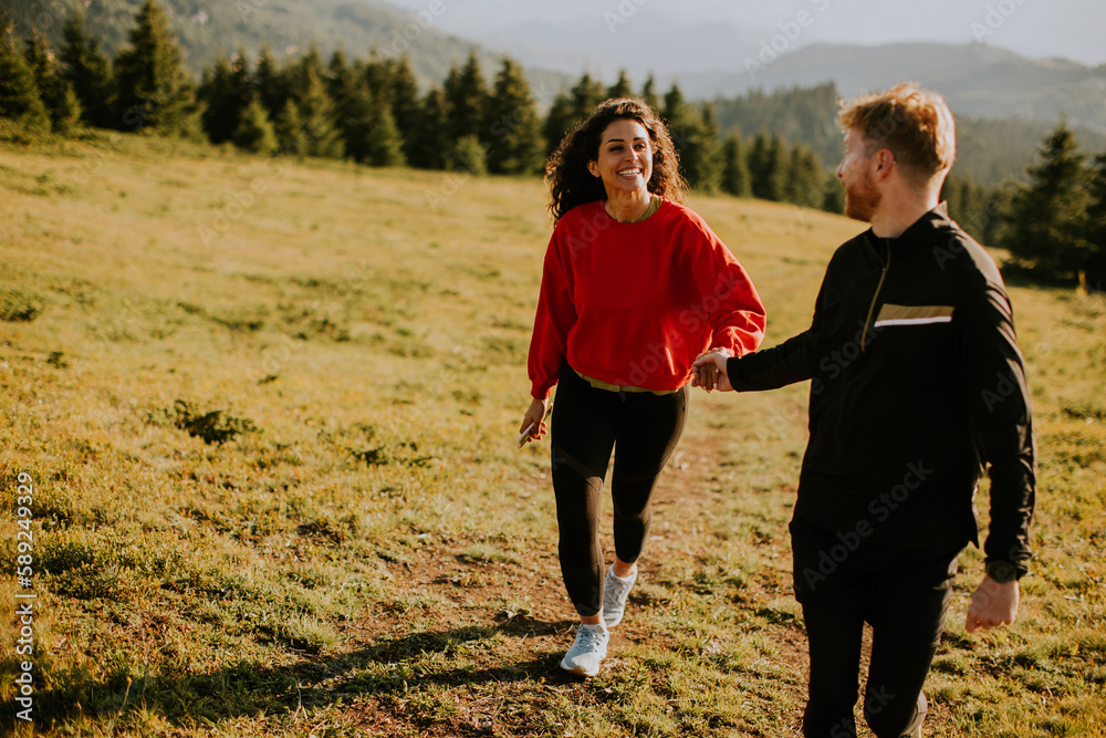 Wall mural smiling couple walking over green hills