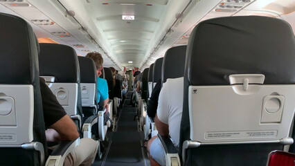 Back of airplane interior. passenger perspective in plane corridor - obrazy, fototapety, plakaty