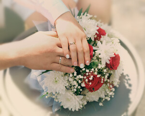 Hands of the newlyweds on the wedding bouquet