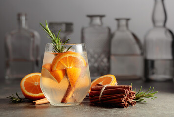 Cocktail gin tonic with ice, rosemary, cinnamon, and orange.