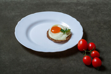 Steak with egg and tomatoes on a white plate