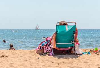 back view of girl sitting on chair on a chair on the beach