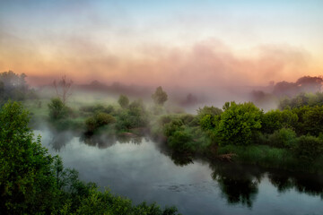 foggy dawn on the green river. Fog over the water. dark morning photo.