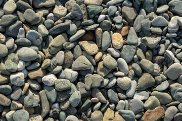 Different color beach stone pebbles at seashore outdoors top view.