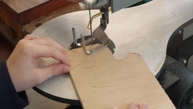Boy cuts board for slicing bread on machine. Labor training lesson. Teacher helps student to make blank from wood. Gift for mom. Plywood products. DIY school project. High quality HD footage