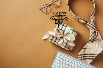 Happy Fathers Day composition. Flat lay gift box, vintage necktie, glasses, keyboard on brown background.