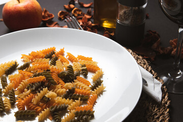 Fusilli pasta on a white plate with an apple and spices