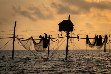 Silhouette of fishermen pulling a nets on fishing poles at sea in Tra Vinh province, Vietnam, Asia during sunrise, local people call it is Day hang khoi.