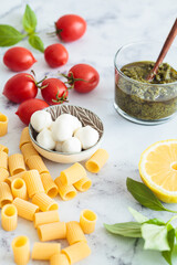 Raw ingredients for making vegetarian pasta with tomatoes, pesto and mozzarella. Italian cuisine concept.