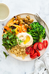 Balanced quinoa salad with broccoli, hummus, olives, carrots and parsley. Vegan detox food concept.