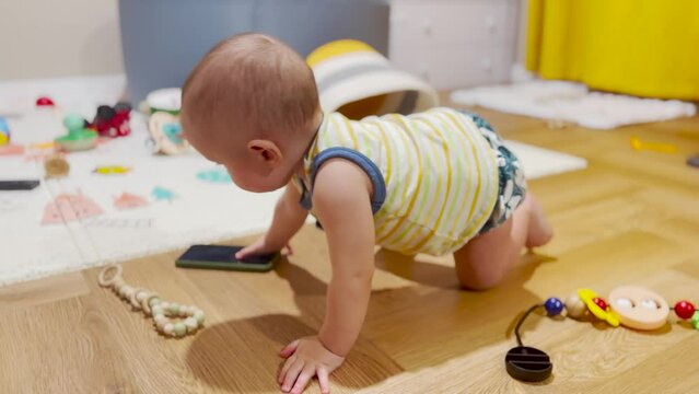 Baby kid is play with the phone on the floor. funny baby with a pacifier explores the phone sits on the floor play shakes his hand. happy family kid dream concept. baby play lifestyle with smartphone