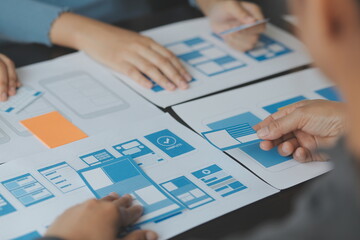 Close up ux developer and ui designer brainstorming about mobile app interface wireframe design on...
