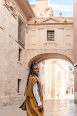 Fototapeta na wymiar smiling African American woman with braids walking through the streets of Valencia in Spain
