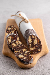 Sweet salami on a wooden board on a gray table.