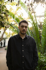 Young man is standing in front of different kind of trees.