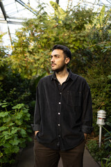 Young man is standing in front of different kind of trees.