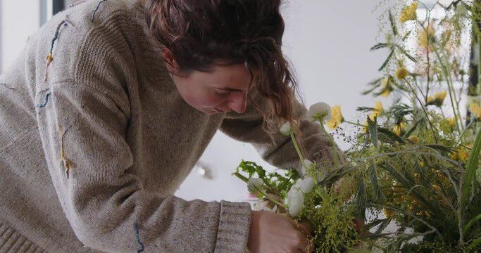 female doing new bouquet. Girl working in flower shop studio. Female florist artist cleans flowers for a beautiful bouquet, workplace view. High quality 4k footage