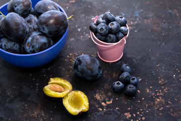 Ripe juicy plums and blueberries in a bowl on a table. Summer fruits.